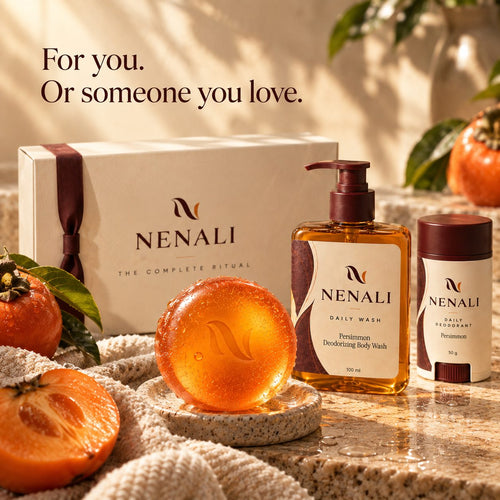For you, or someone you love: the NENALI gift box with the round persimmon bar, the Daily Wash and the Daily Deodorant, beside whole and halved persimmons