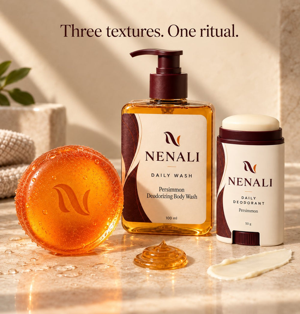 Three textures, one ritual: the round persimmon bar, the Daily Wash and the Daily Deodorant on stone